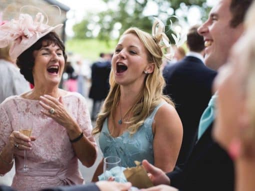 Two women laughing and gasping at magic trick at garden reception